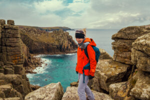 Lady walker in bright coat walking the South West Coast Path, Cornwall